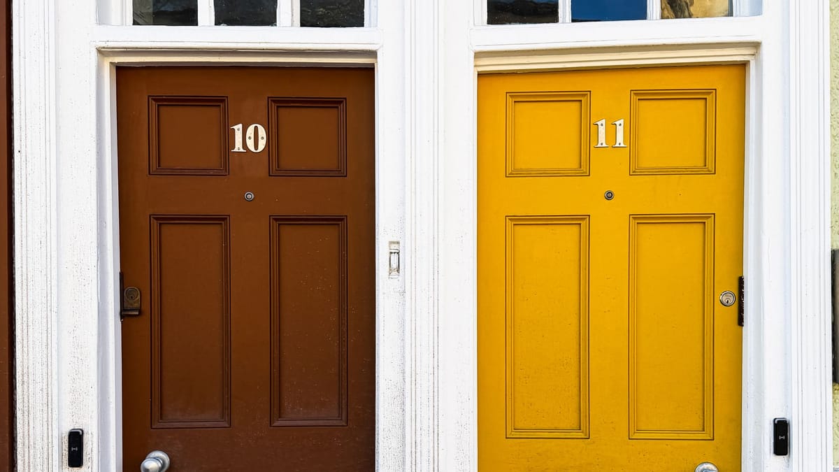 A brown door and a yellow door side by side on a white wall