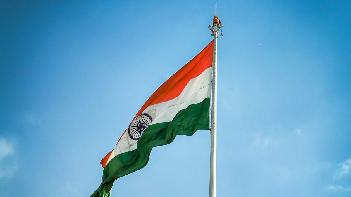 The Indian flag flying on a pole against a blue sky