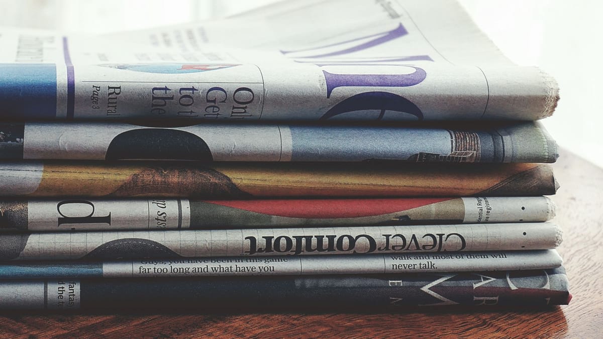 A stack of folded newspapers on a wooden table