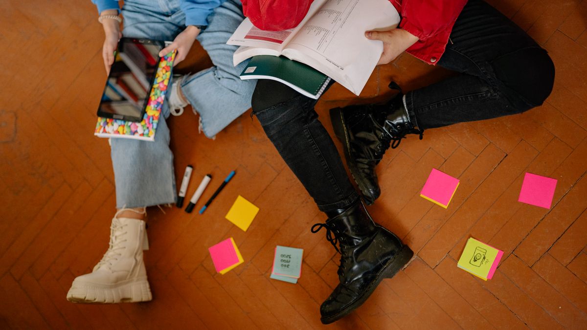 Two students surrounded by books, notes and sticky notes while studying